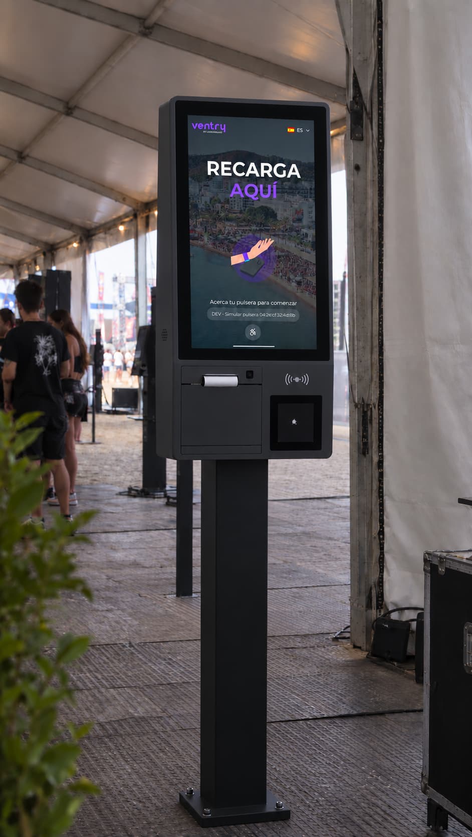 Kiosco de autorrecarga de VENTRY en un festival, con la pantalla «Recarga aquí» y el lector de pulseras